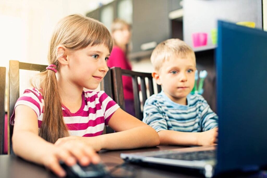 Two young children learning Persian online using a laptop.